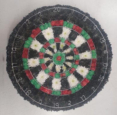 A dartboard featuring red, green, and white sections with aluminium  numbers around the edge.